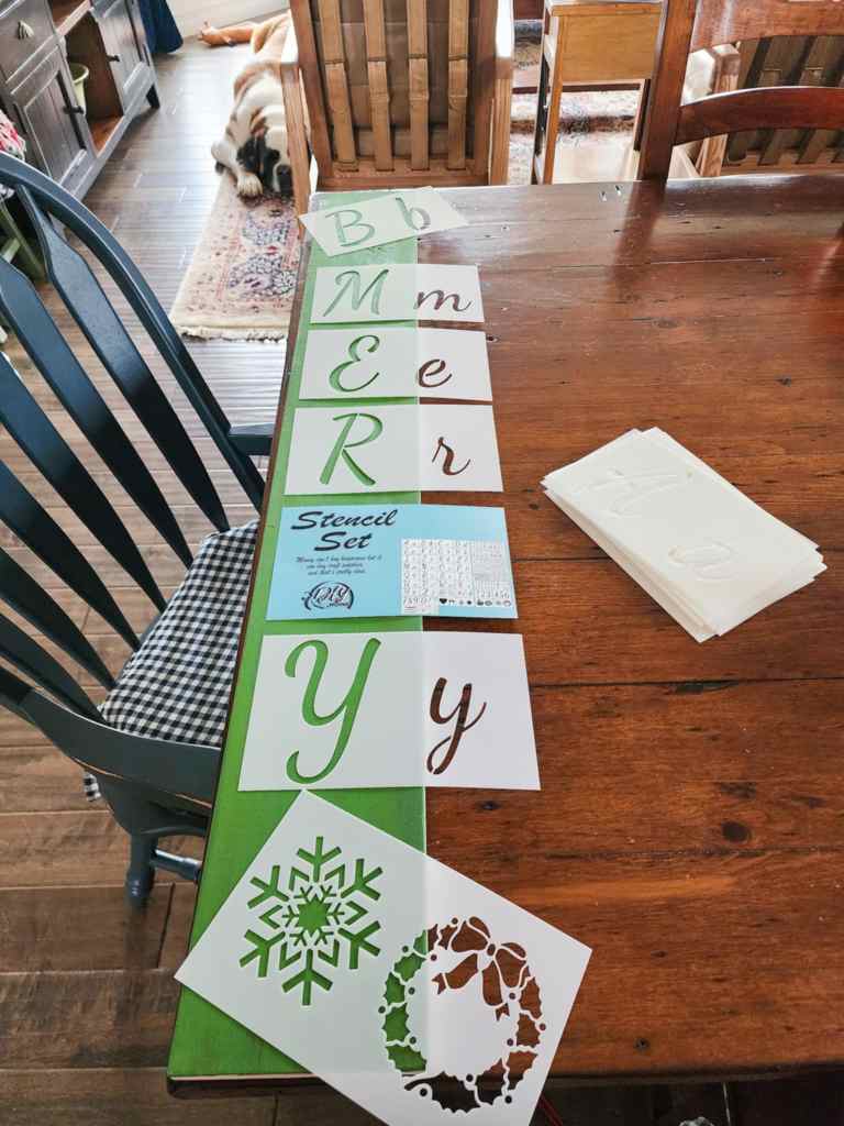 Letter stencils laid out on a board to make a Christmassy porch sign.  