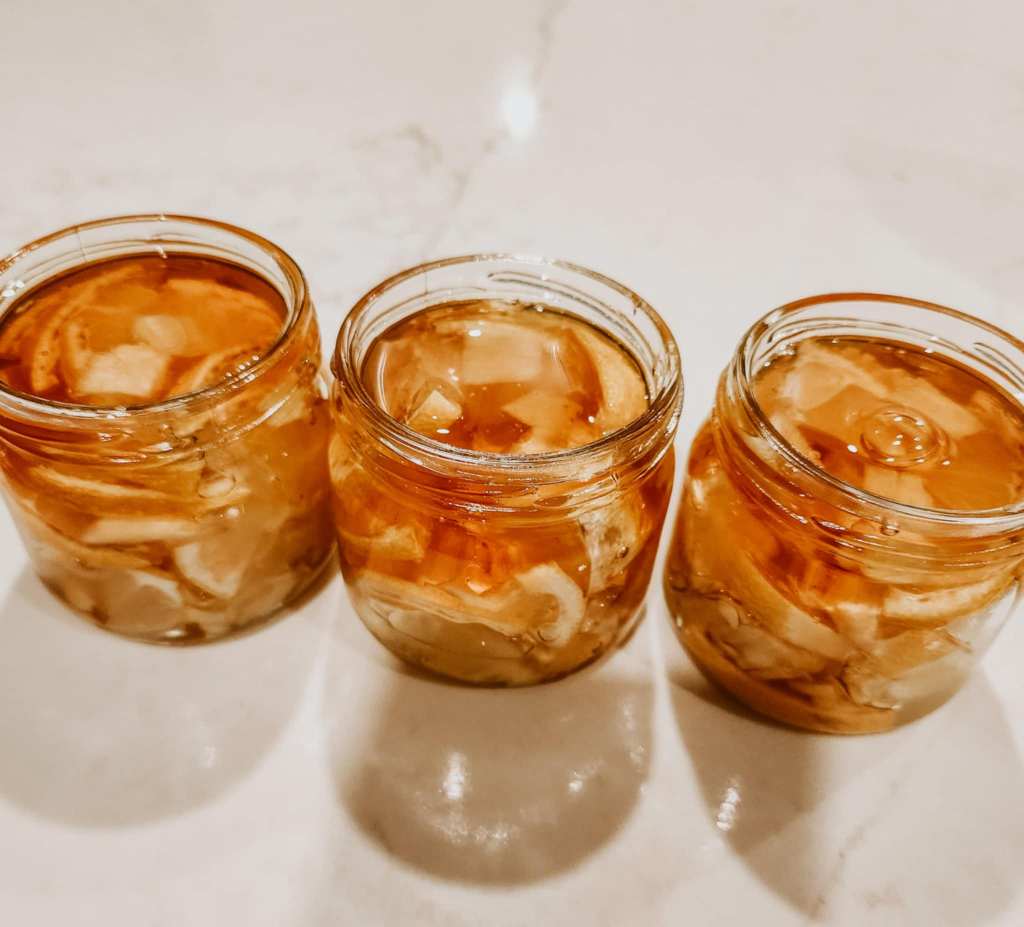 3 jars of homemade anti-flu brew with the honey glistening on top of the lemon slices. 