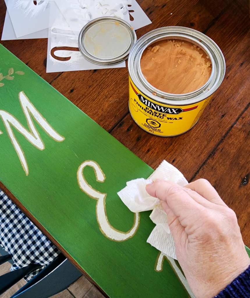 Applying paste wax to a porch sign for weather proofing. 
