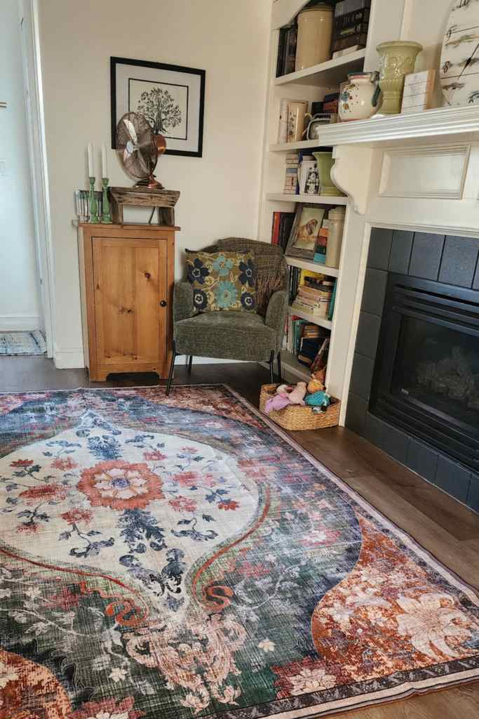A sitting room corner with a large machine washable rug, a green chenille chair, and a basket of dog toys. 