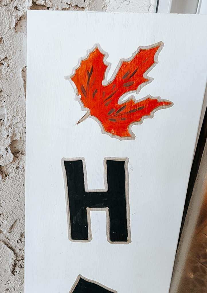 A white porch sign with a maple leaf on it. 