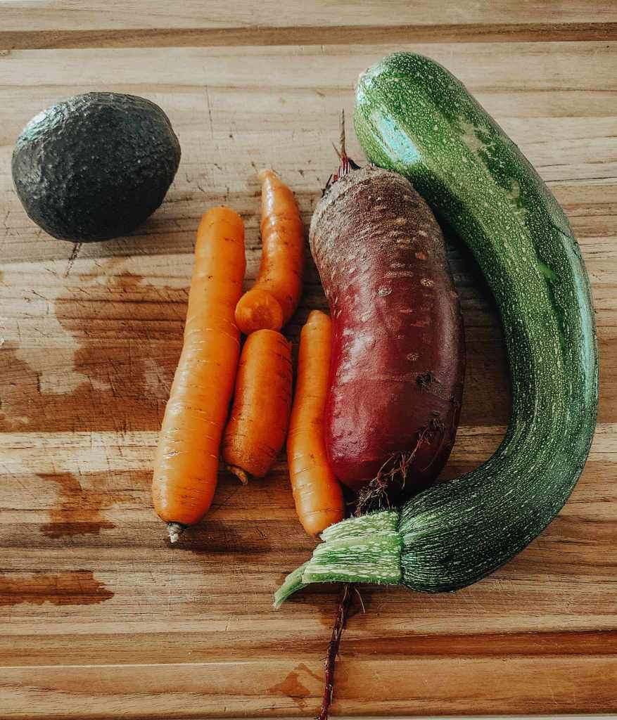 Some carrots, beets, and zucchini on a cutting board.