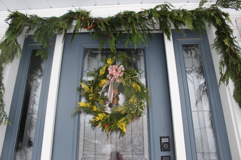 A holiday doorway with fresh greenery wreath and garland. 
