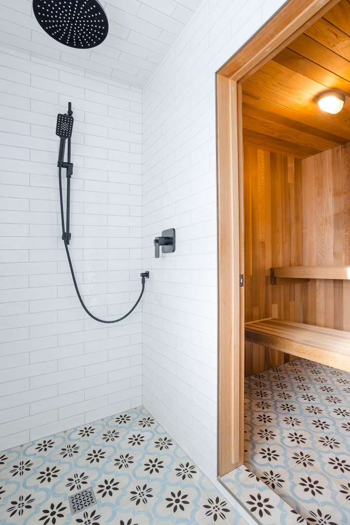 A sauna and shower with white subway tiles on the floor, and pretty blue and brown patterned concrete tiles on the floor. Prefect for a dog washing zone. 