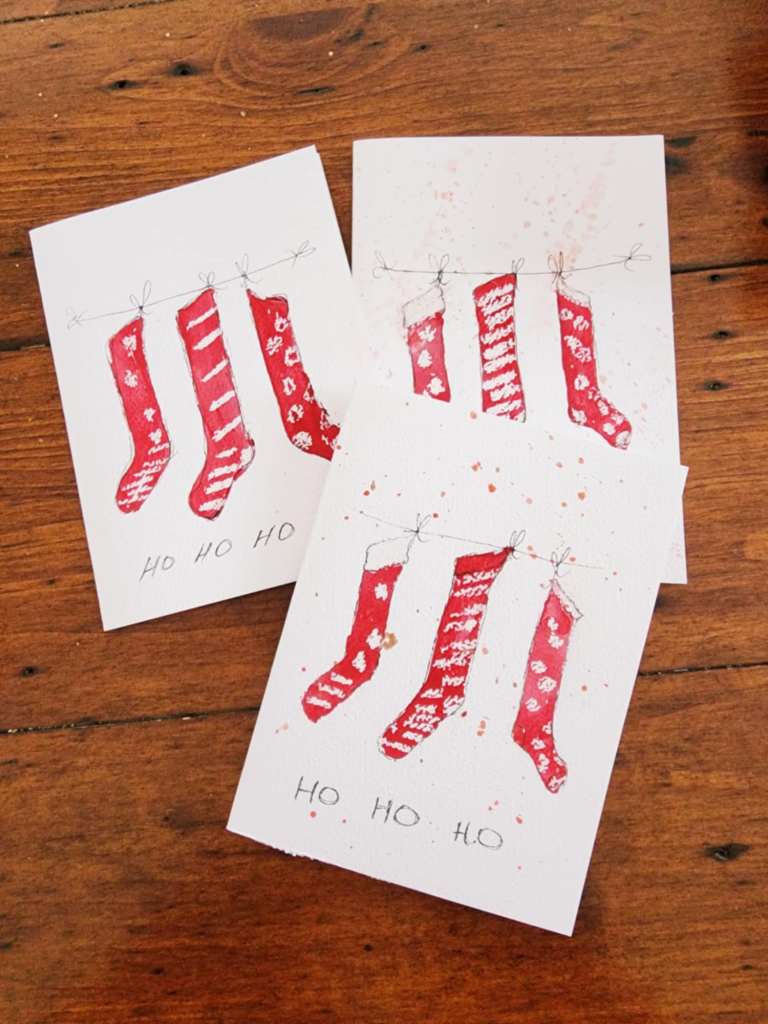 A watercolour diy Christmas card with a trio of stockings on front.  