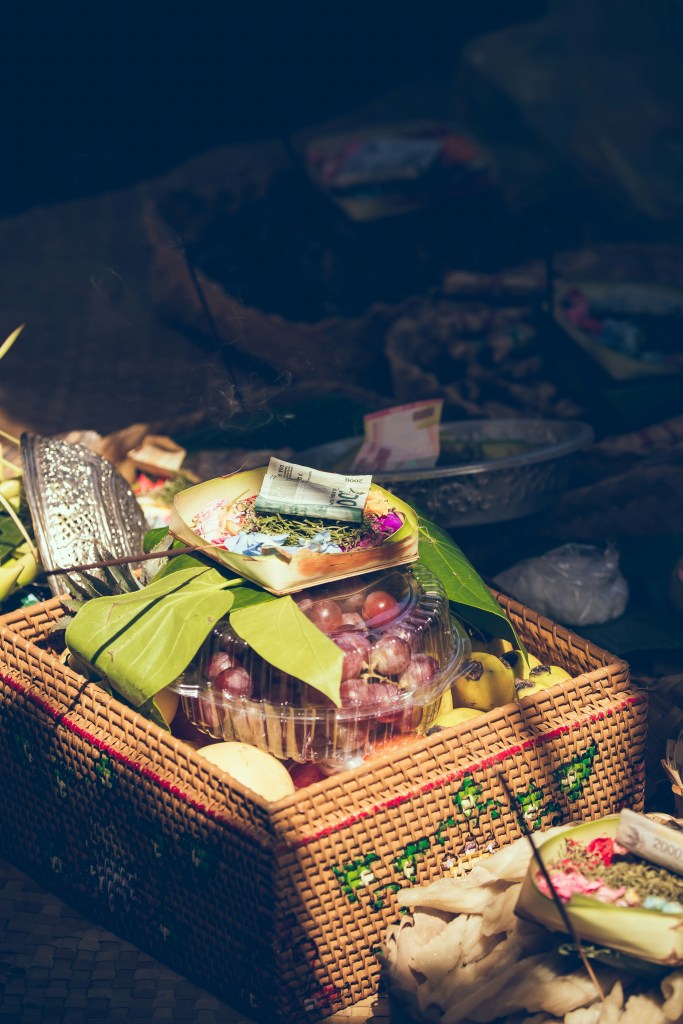 A picnic type gift basket with grapes, food items, a baking dish, and money.  