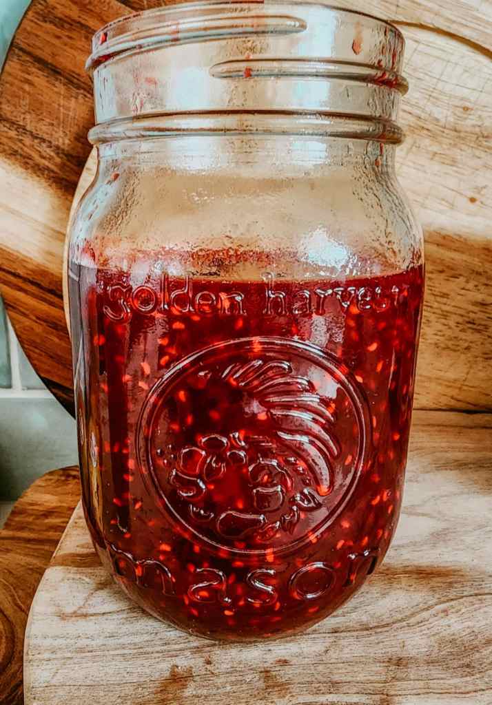 A jar of newly made pectin-free small batch raspberry jam. 