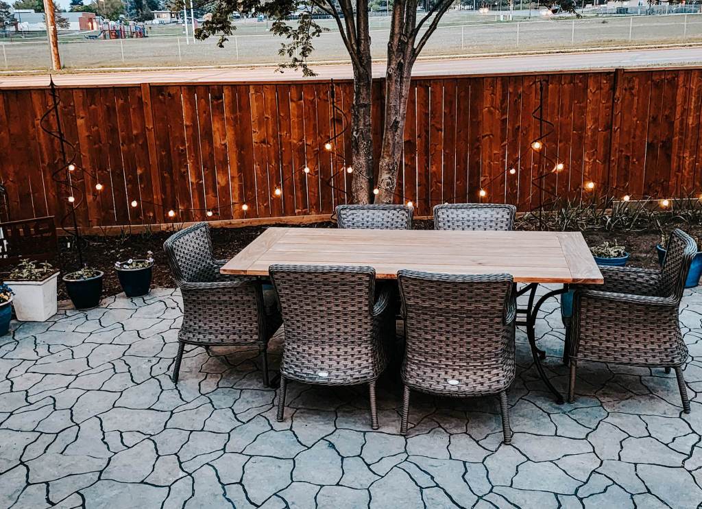 A new interlock patio, with solar string lights and a new patio table and wicker chairs. 