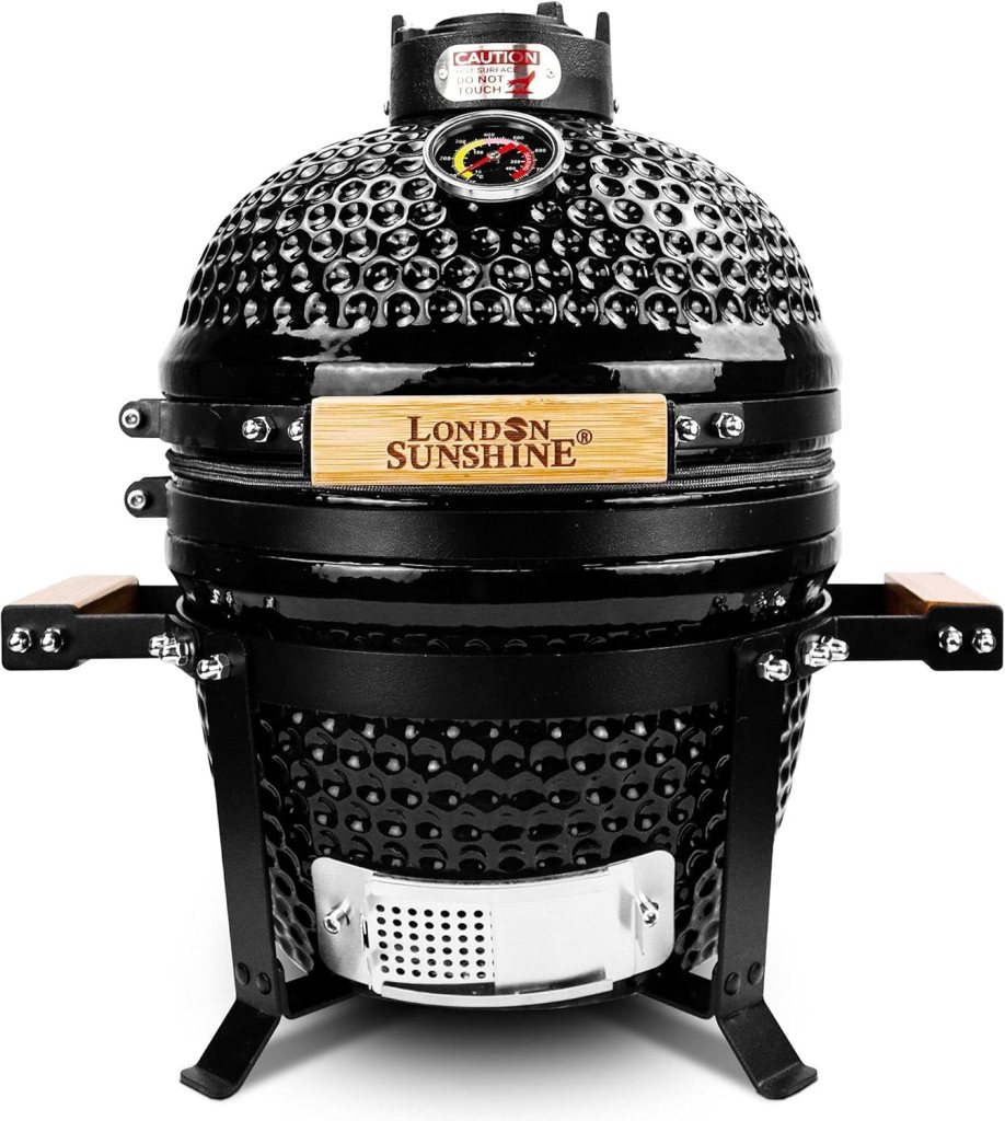 A black portable kamado-style grill with a textured surface and wooden handles, showcasing a temperature gauge on the top.