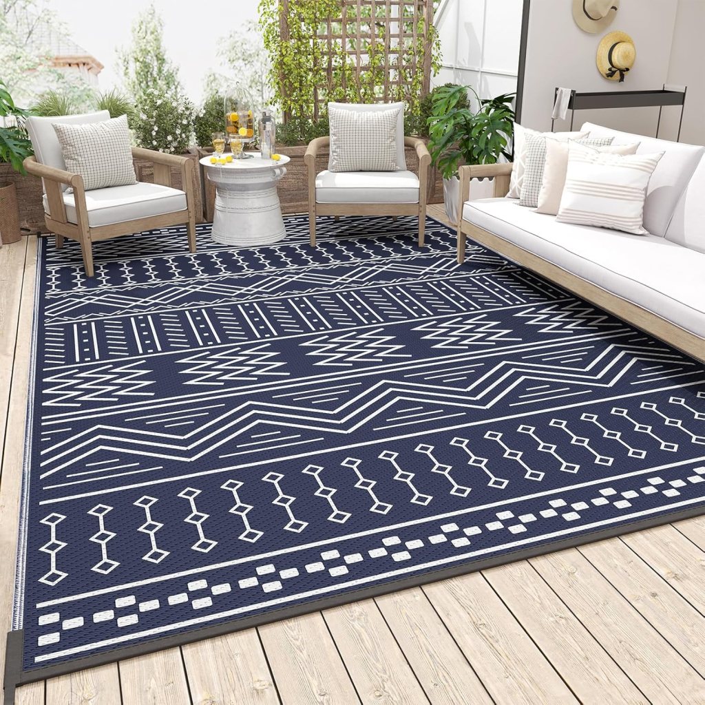 Outdoor seating area with stylish navy rug featuring geometric patterns, surrounded by patio furniture and greenery.