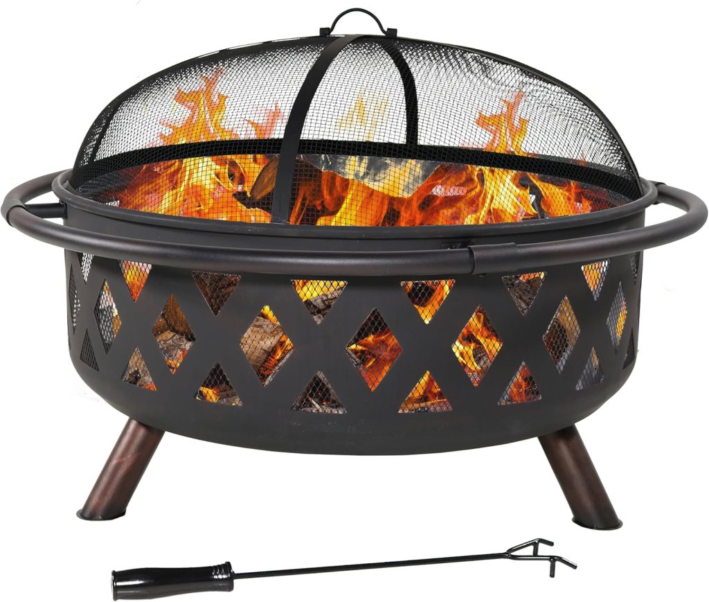 A black fire pit with a mesh top and flames visible inside, placed on sturdy legs, alongside a poker tool.