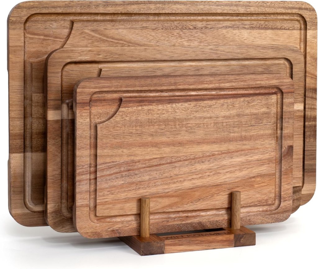 Set of three acacia wood cutting boards displayed on a stand, showcasing a natural wood finish.