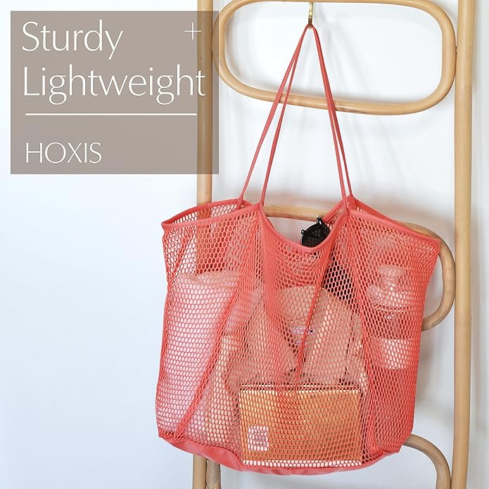 A sturdy and lightweight mesh tote bag in coral color displayed on a wooden rack, designed for beach or casual outings.
