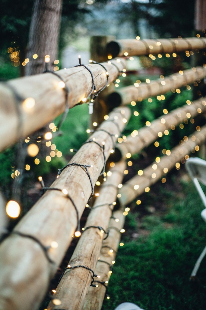A close-up view of wooden garden fencing adorned with string lights, creating a warm and inviting ambiance.