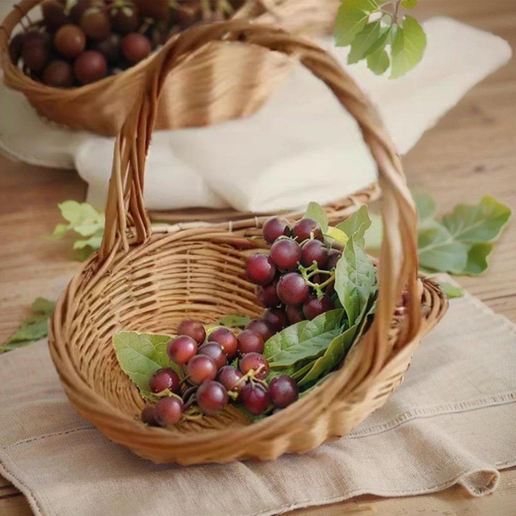 A wicker basket filled with dark purple grapes and fresh green leaves, placed on a wooden table.