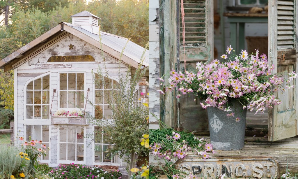 A rustic garden shed with large windows and a peaked roof, surrounded by greenery and flowers, with a metal bucket of pink flowers at the entrance.