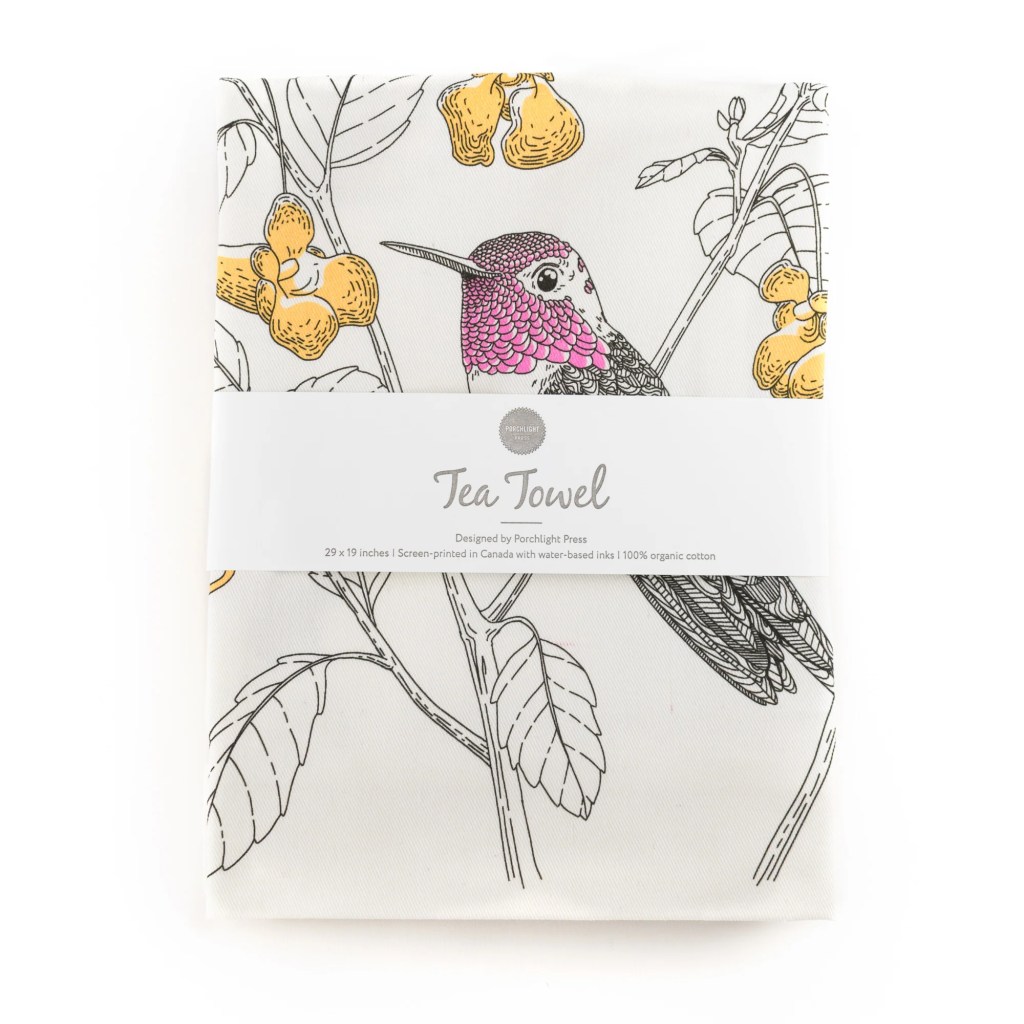 A folded tea towel featuring a colorful illustration of a hummingbird and yellow flowers, with a label that reads 'Tea Towel'.