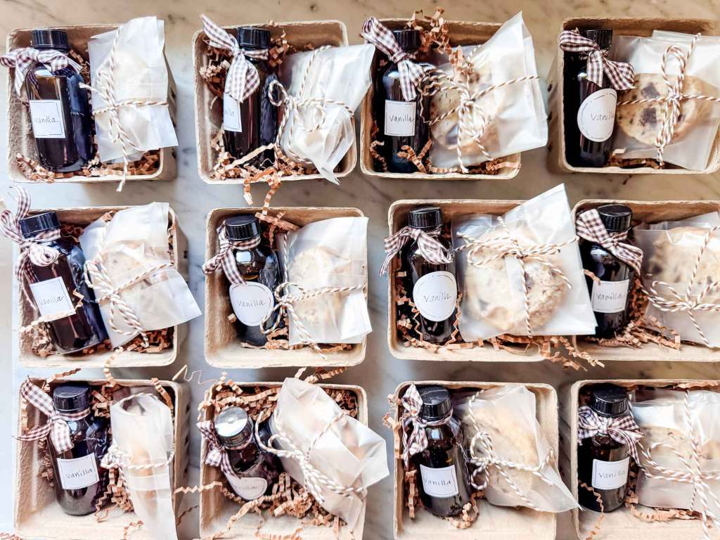 Rows of gift boxes containing homemade vanilla extract and cookies, decorated with twine and labels.