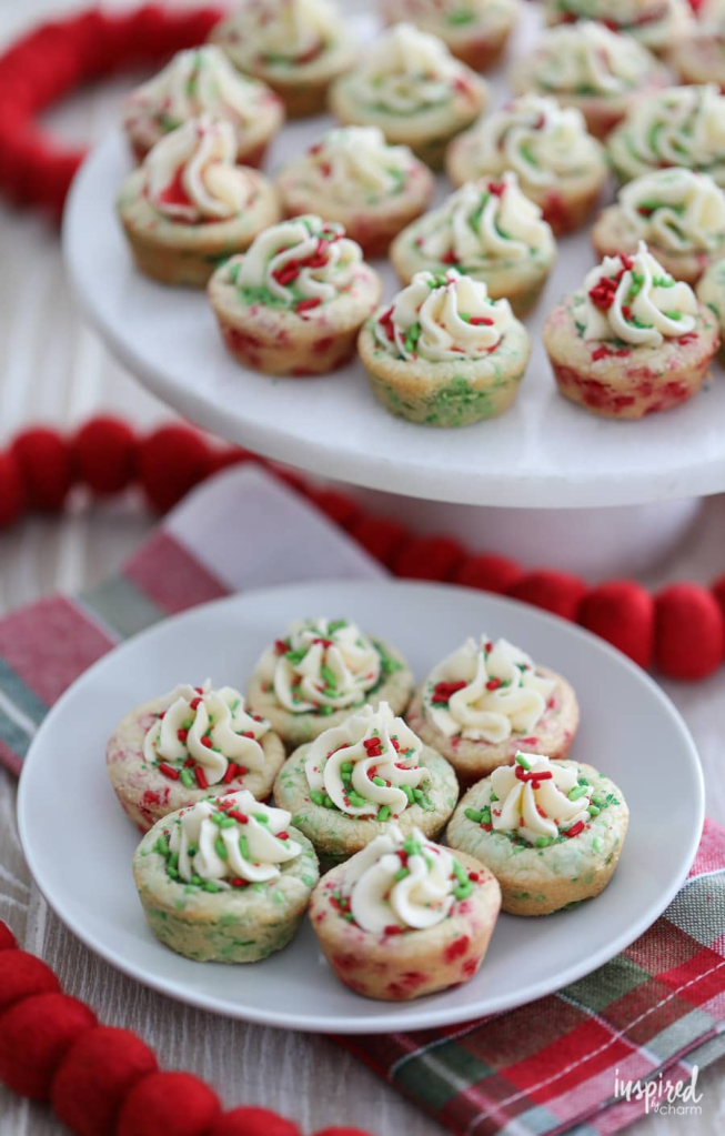 A plate of festive cookie cups decorated with red and green sprinkles and white frosting, set against a plaid background.