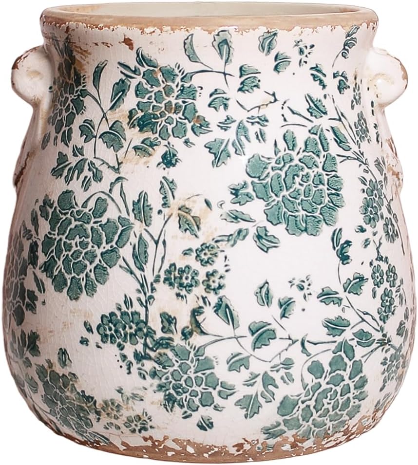 A vintage ceramic vase featuring a floral pattern in shades of green on a white background, with a slightly worn texture and two small handles.