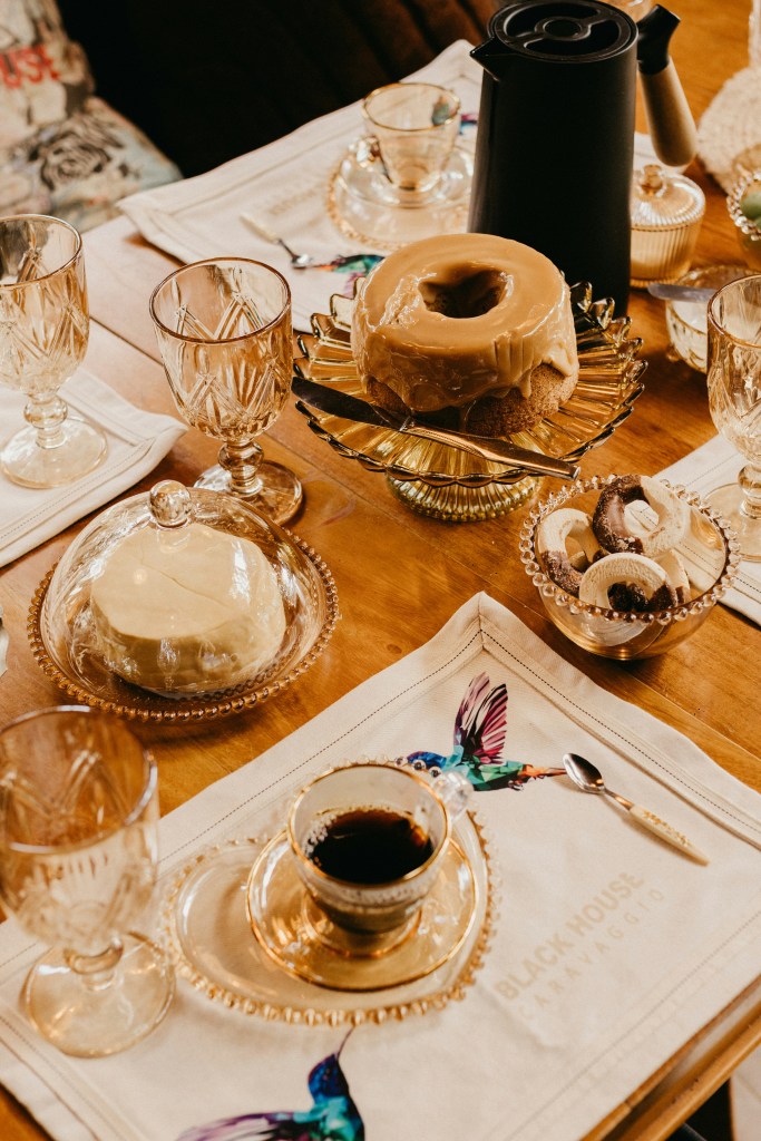 A beautifully arranged table with two types of cakes, a coffee pot, and elegant glassware, showcasing a cozy dessert setting.