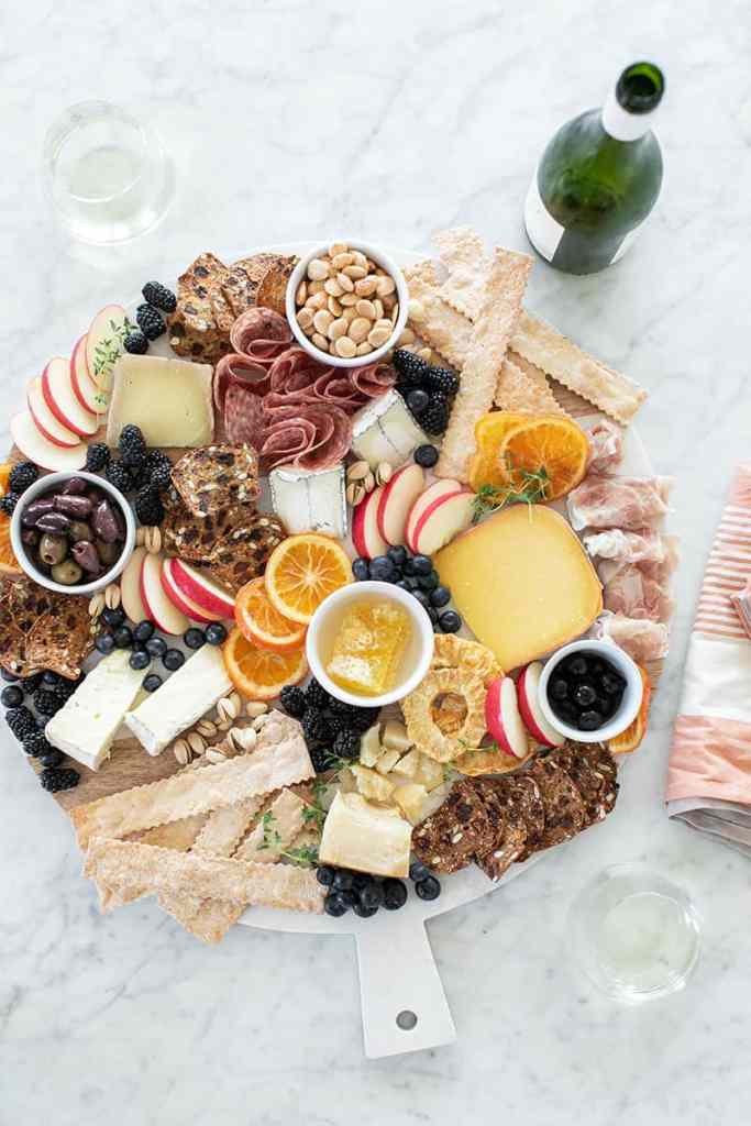 A charcuterie board with fruits, meats, crachers, and cheeses.  